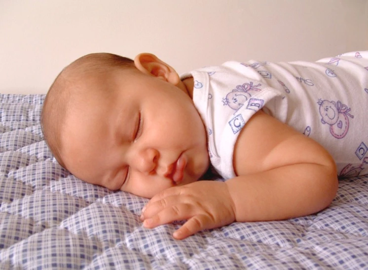 a baby is sleeping on a bed wearing pajamas