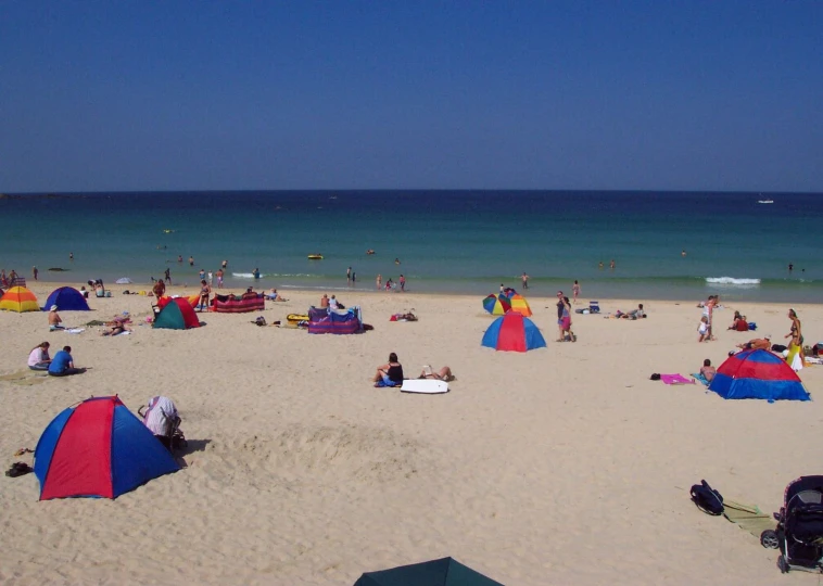 a large beach with people on it and an ocean in the background