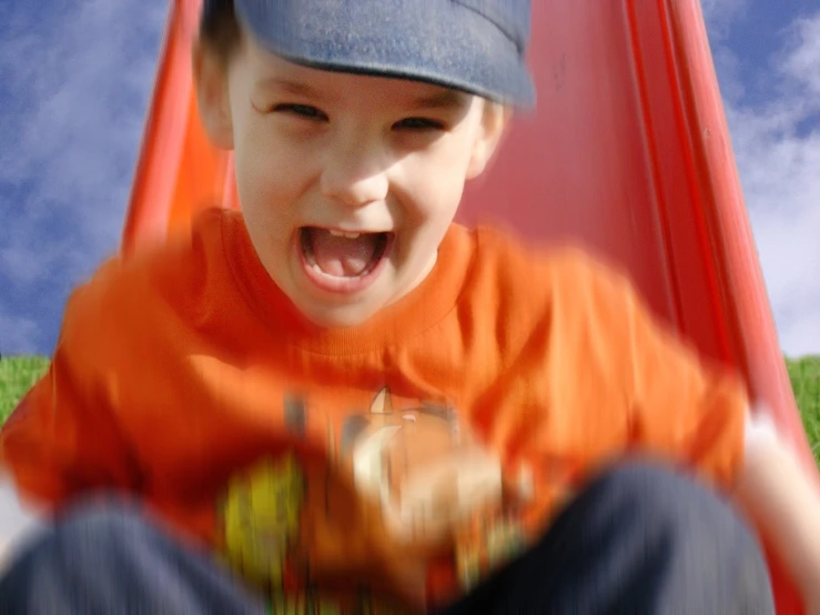 a  riding on top of a slide in a park