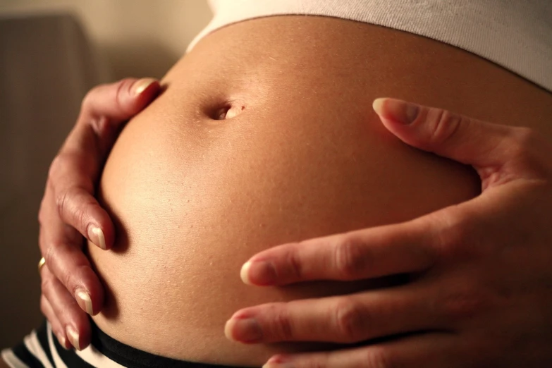 a close up of a persons hands on the belly of someone