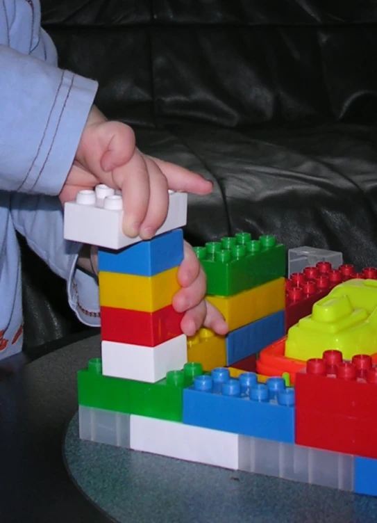 a toddler holding the hand of a lego toy