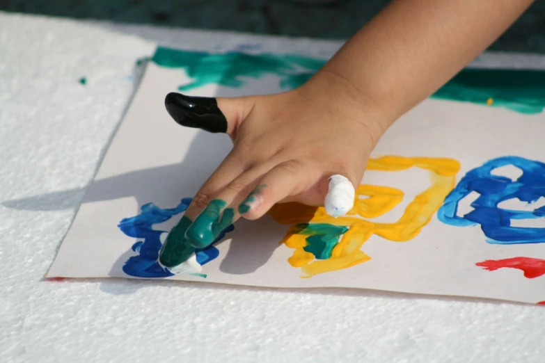 a child holding their hand on a piece of art