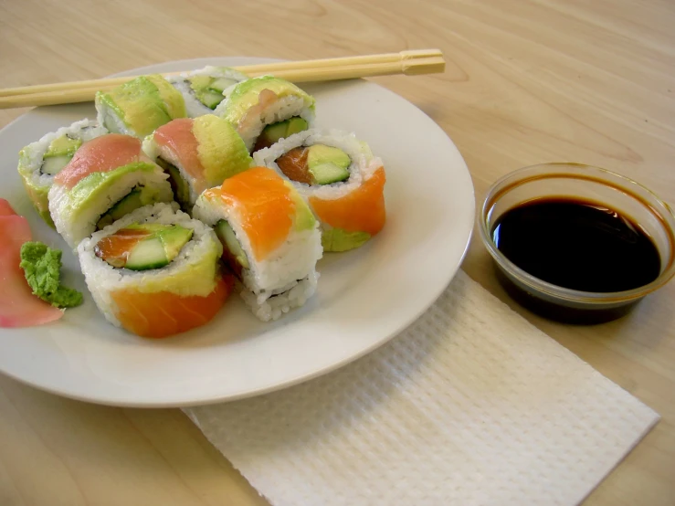 sushi and sesame seeds served on a plate next to dipping sauce