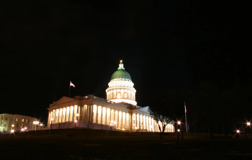 an illuminated building with a lit up flag and clock tower