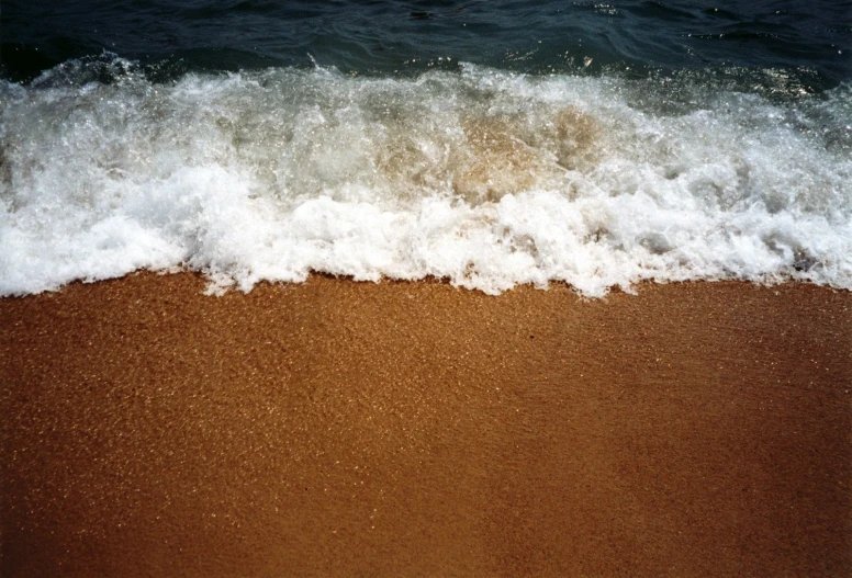 a wave crashes into the sand on the beach