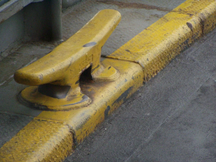 an old yellow and black metal pipe sitting on the side of a road