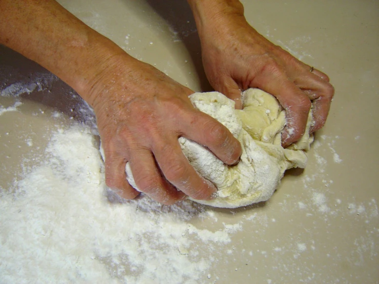 someone in the kitchen kneading soing out of the flour