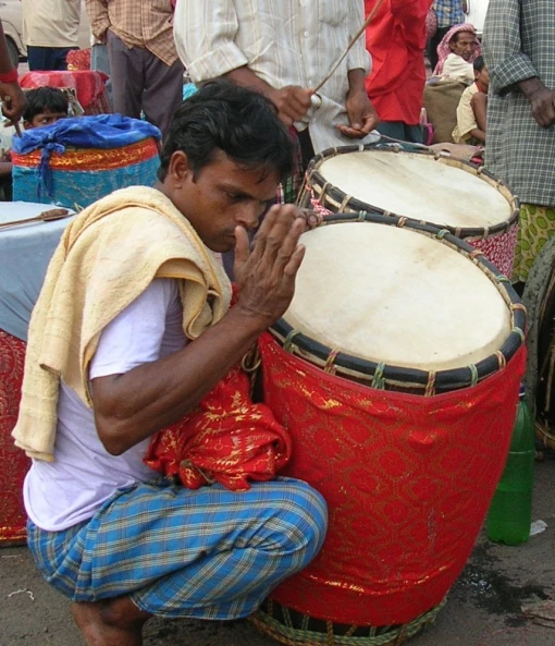 a man kneeling down next to a large drum