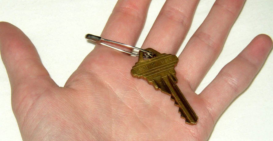 a golden key that is on the palm of someone's hand