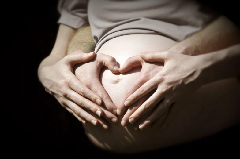 two hands are forming a heart shape in the dark