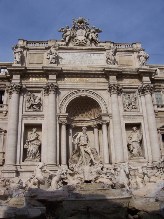 a building has statues and arch doors with sky in background