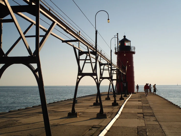 a red light house on the edge of the water near a dock