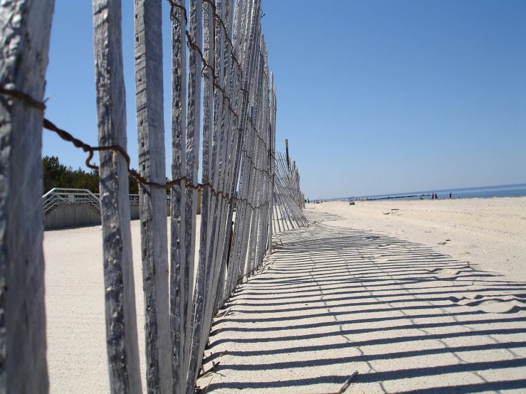 a row of beach fences sit along the sand at a beach