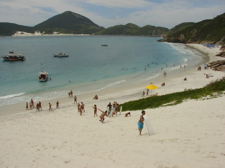 a beach filled with lots of people and a small yellow umbrella