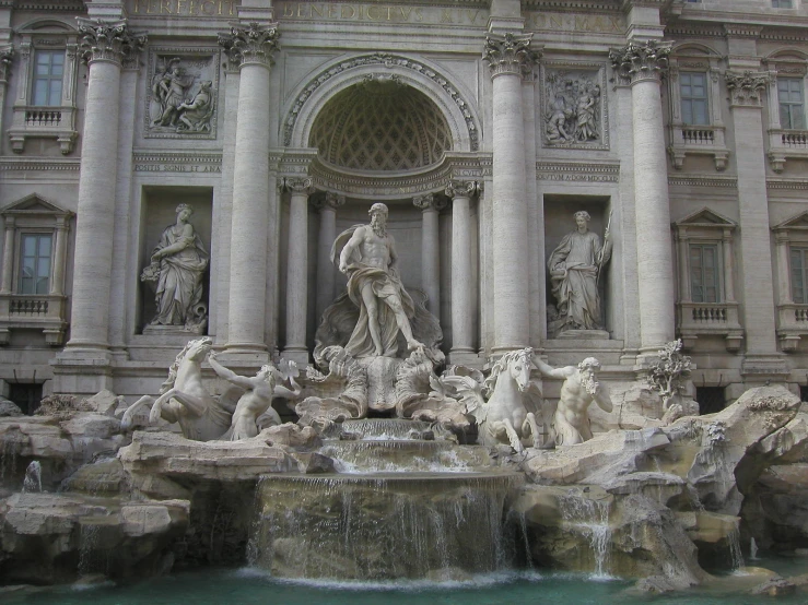 a statue on top of a fountain in front of a building