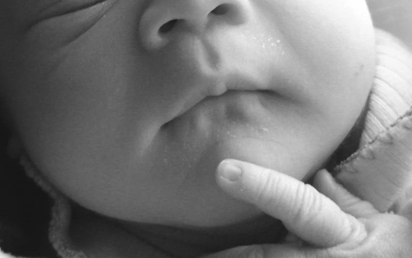 an infant lays on his chest holding its hand up to the side