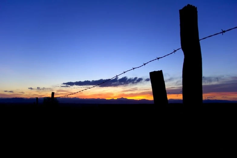 some barbed wire in the dark against a sunset