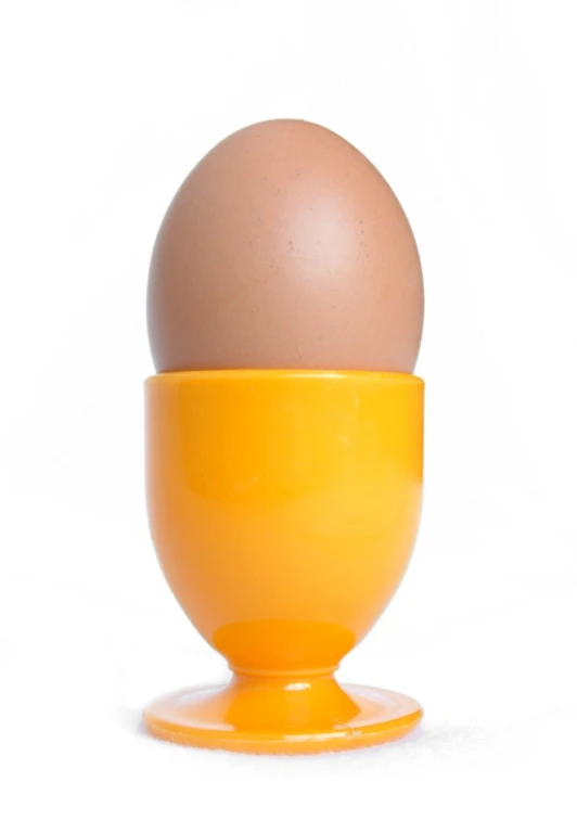 an egg in an orange cup on top of a white background