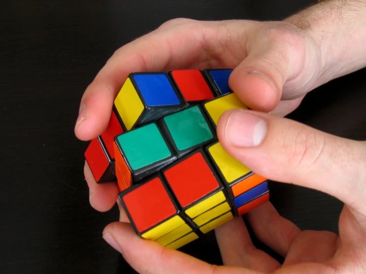 a hand is holding a multicolored rubik cube