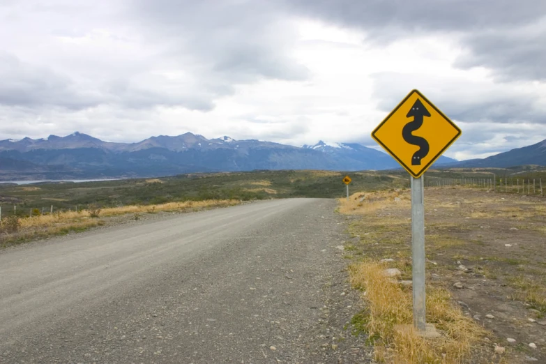 the road is lined with hills and dry grass