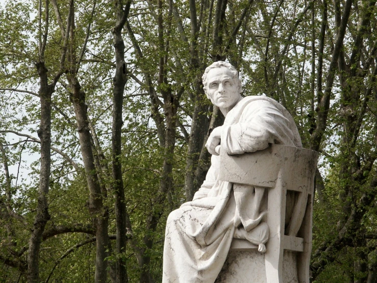 a statue of the roman catholic priest in front of trees