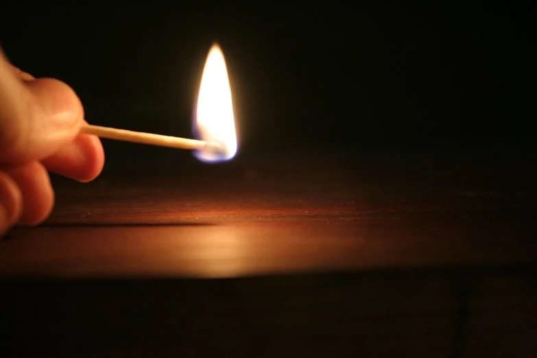 hand lighting a match on a dark table with blurry background