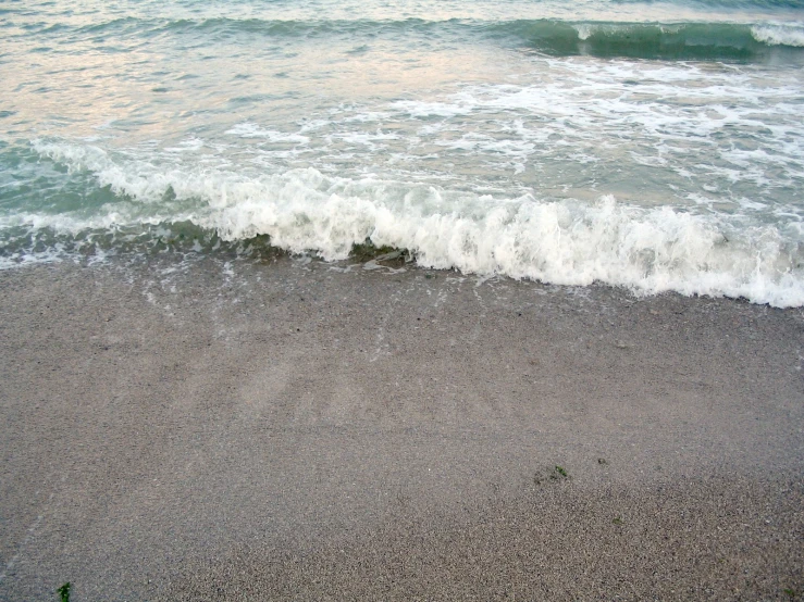 the waves are rolling in to shore next to the beach