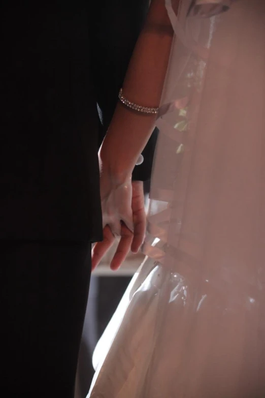 a close up of the bride and groom holding hands