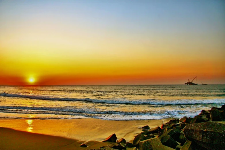 a boat on the beach in front of a setting sun