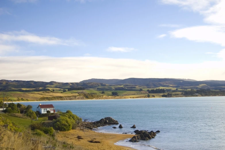 a house next to water surrounded by land and mountains