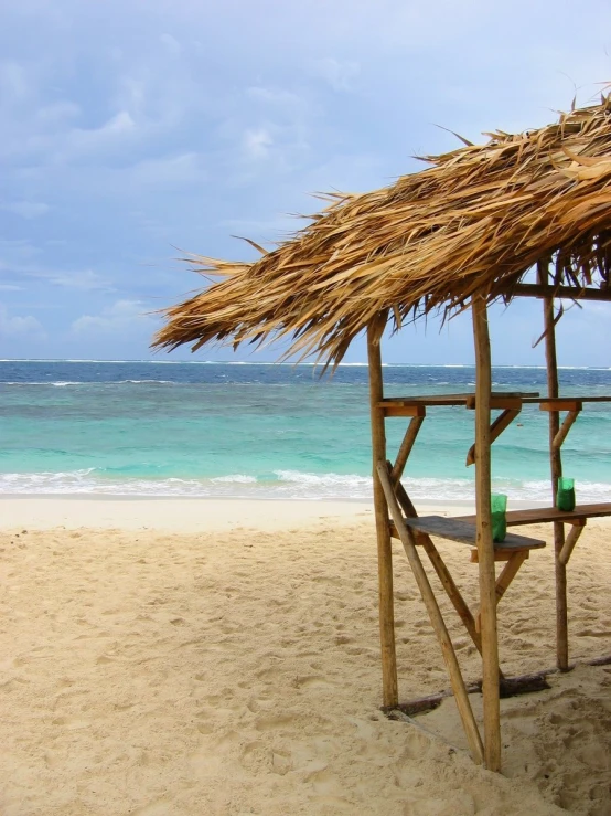 a hut set on top of a beach with a drink bottle under it