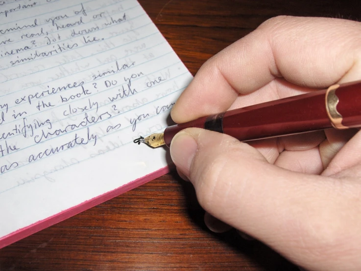 a person holding a pen and looking at a note