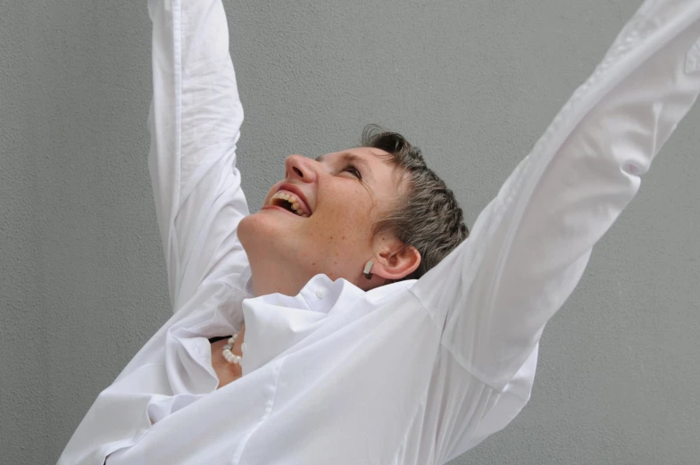 a woman in white shirt laughing while holding a kite