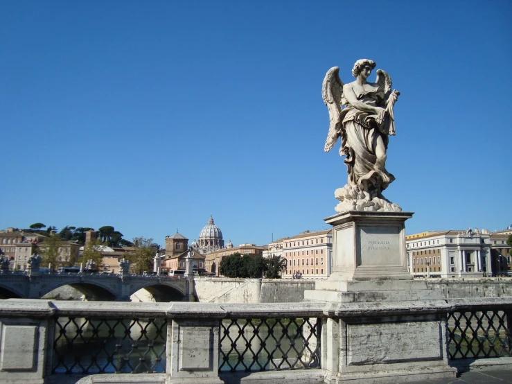 a statue of an angel standing on top of a concrete bridge