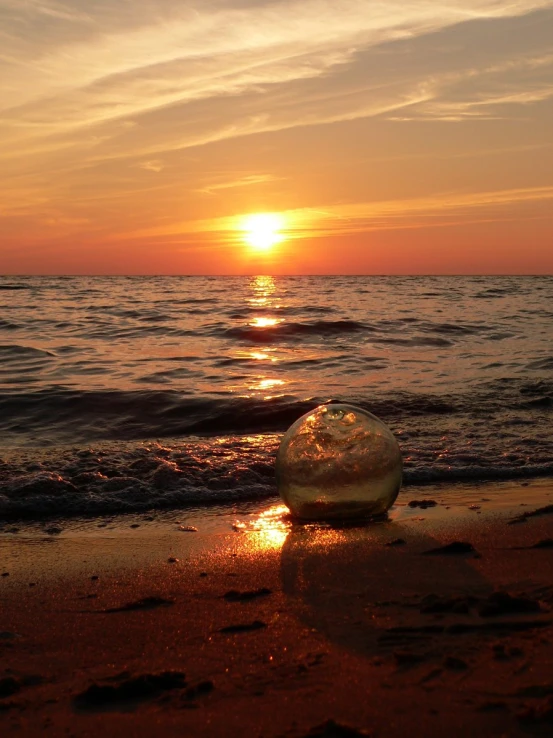 the sun is setting over the ocean on a beach