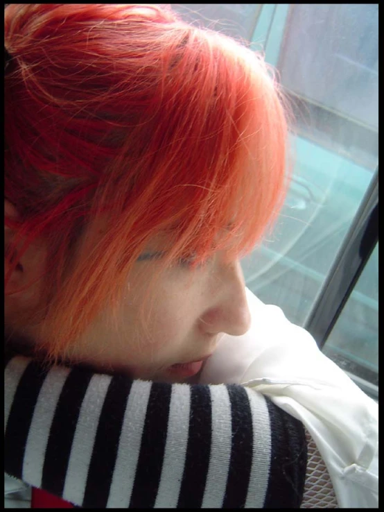 a  with red hair is sitting by the window