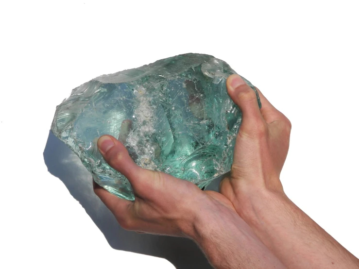 a person holding up a green rock in their hands