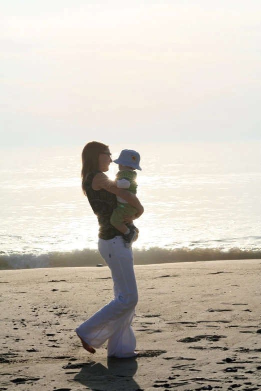 a woman with a baby in her arms on the beach