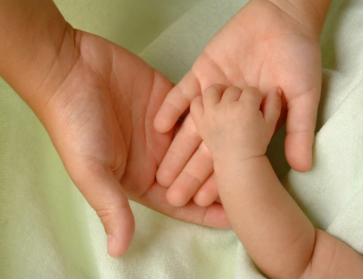 a woman holding the hands of a baby