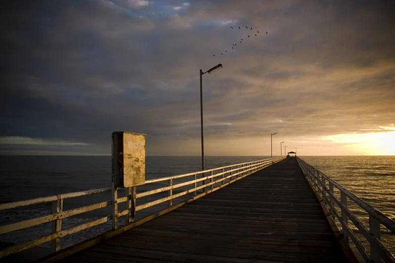 a pier with birds flying over the water