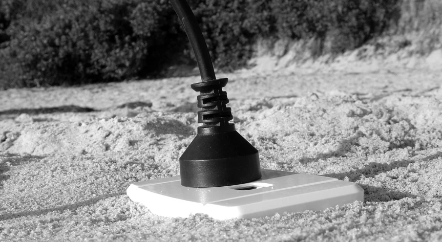 a black and white po of an upside down light in the sand