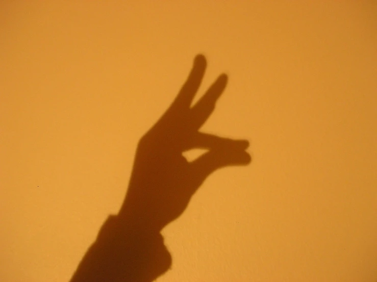 the shadow of someone's hand reaching up to a banana