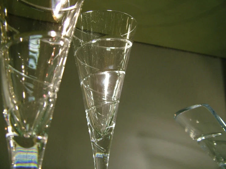 two clear glasses on a table with one empty