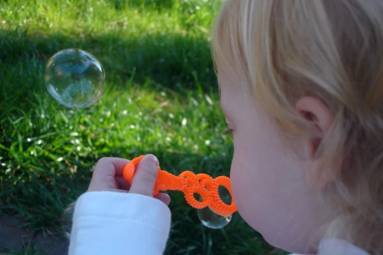 a little girl holding a pair of scissors near bubbles