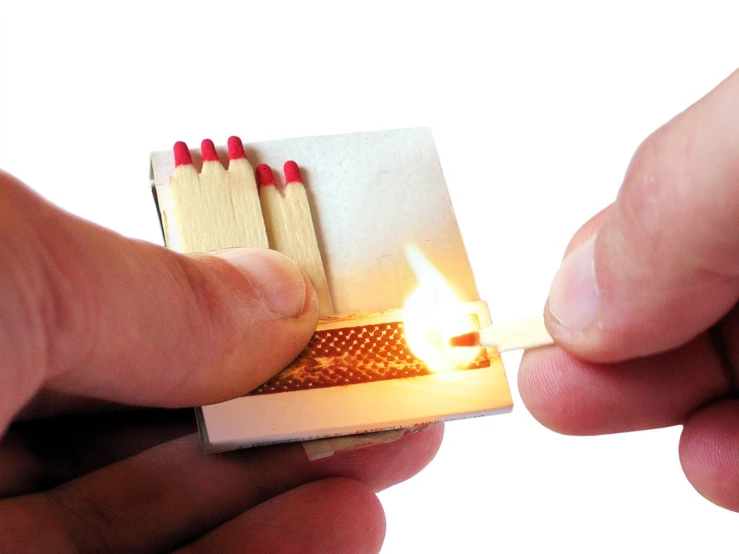 a person holding a match box lighter next to a match