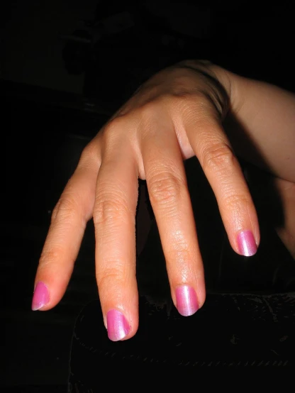 hand with pink nail sitting on black stool