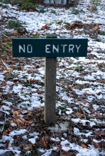 an wooden sign in a snowy ground with no entry