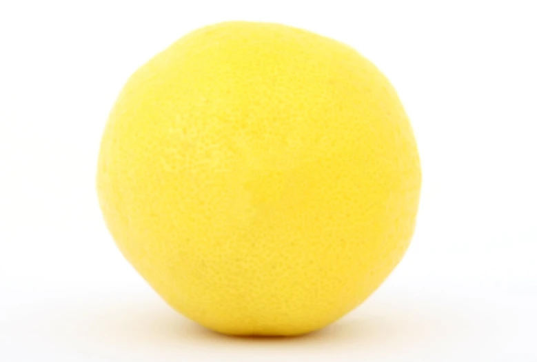 an egg shell next to a lemon on a white background