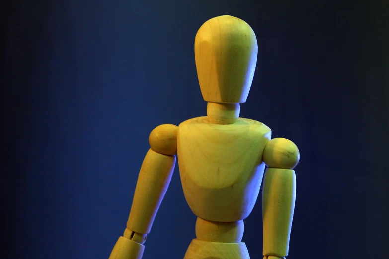 a large toy mannequin posed in front of a dark background