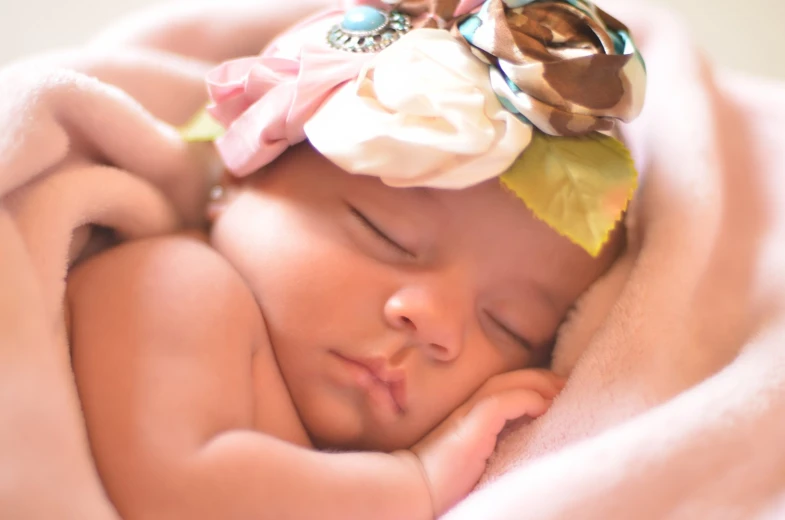 a baby sleeping with a pink blanket on top of it